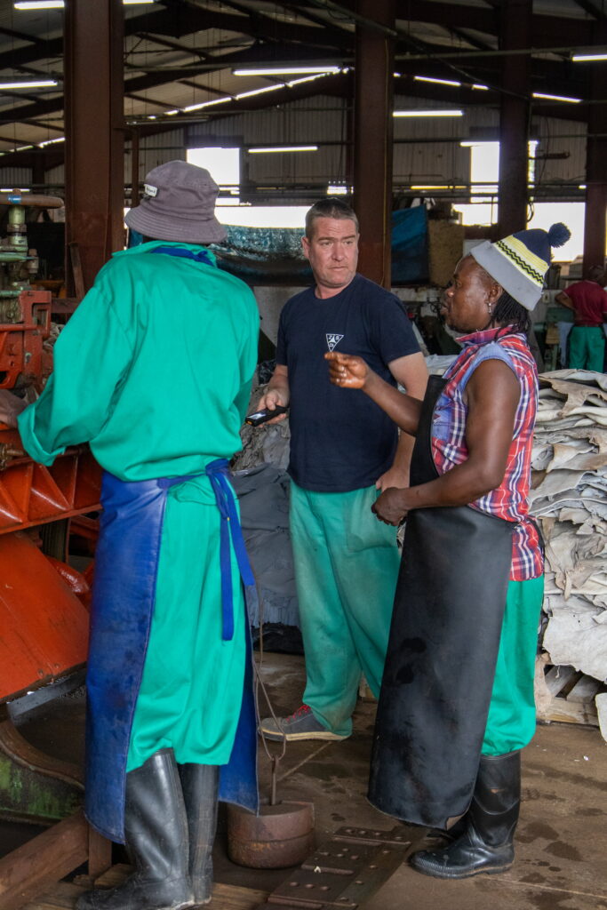 Oasis Tanning Company factory manager discussing work with two staff members on the tannery floor in Randfontein South Africa